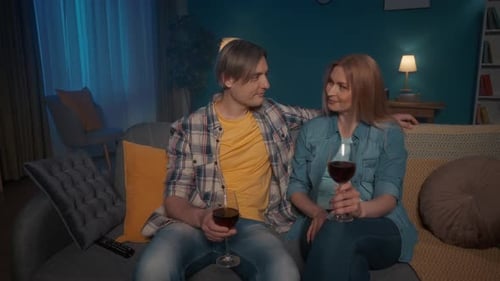 Couple Relaxing on Couch Drinking Wine at Night