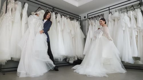 Two Beautiful Brides Choose a Beautiful Wedding Dress in a Wedding Salon
