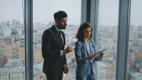 Couple Businesspeople Discussing Collaborative Project Standing Office Window