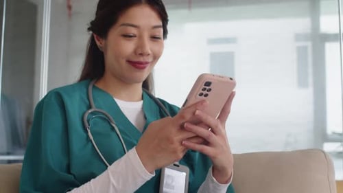 Nurse Chatting with Friends on Smartphone during Break at Work