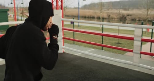 Young Man Training Boxing in Urban Ring