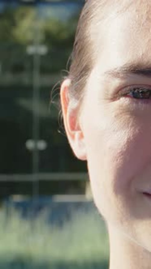 Femme se tournant vers la caméra alors qu'elle effectue un panoramique lent, montrant le visage droit, réagissant à la lumière du soleil, bureau à façade vitrée