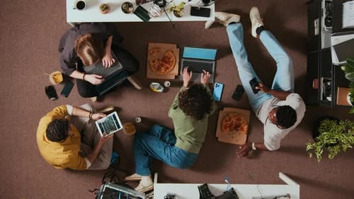 Young People Work Together with Laptops, Eating Pizza
