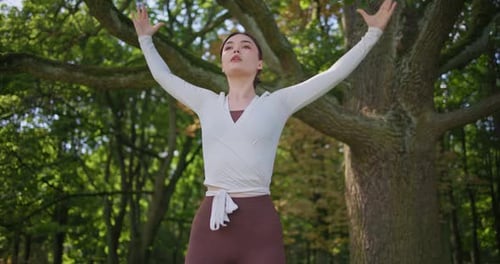 Young Beautiful Athletic Woman in Sportswear Doing Stretching and Warming Up in the Park Near a Tree