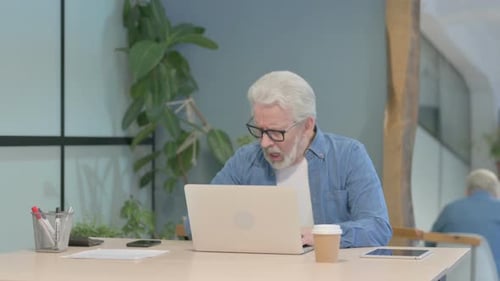 Senior Man Coughing While Working on Laptop