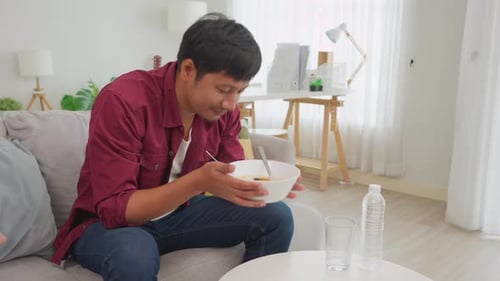 Young Adult Enjoys Noodles in Bright Home