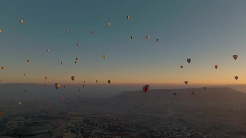 Drone view of hundreds of colorful hot air balloons soaring at sunrise in Cappadocia