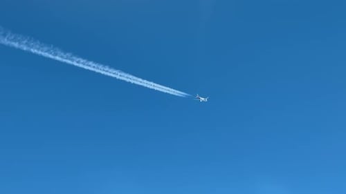 A Jet Airplane and Its Contrail Crossing Diagonally a Blue Sky: View Taken from Another Cockpit