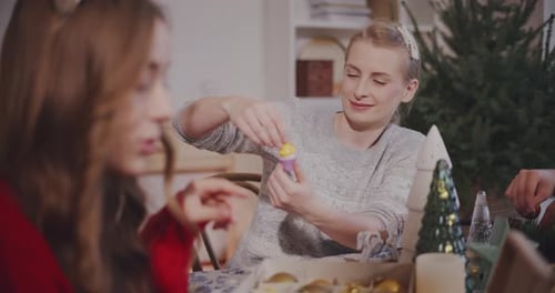 Woman Crafting with Family at Christmas Table