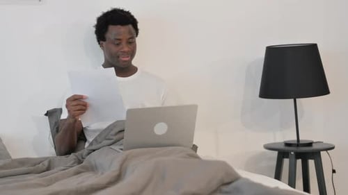 Young Adult Working from Home on Laptop in Bed