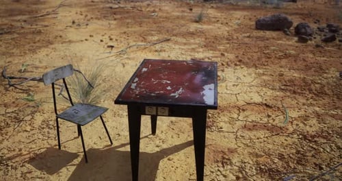 Table and Chair on Dry Ground in a Desolate Landscape During Daytime
