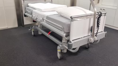 Krankenhausbett auf Rädern vor einem modernen Patientenlift, frisch zubereitet und einsatzbereit