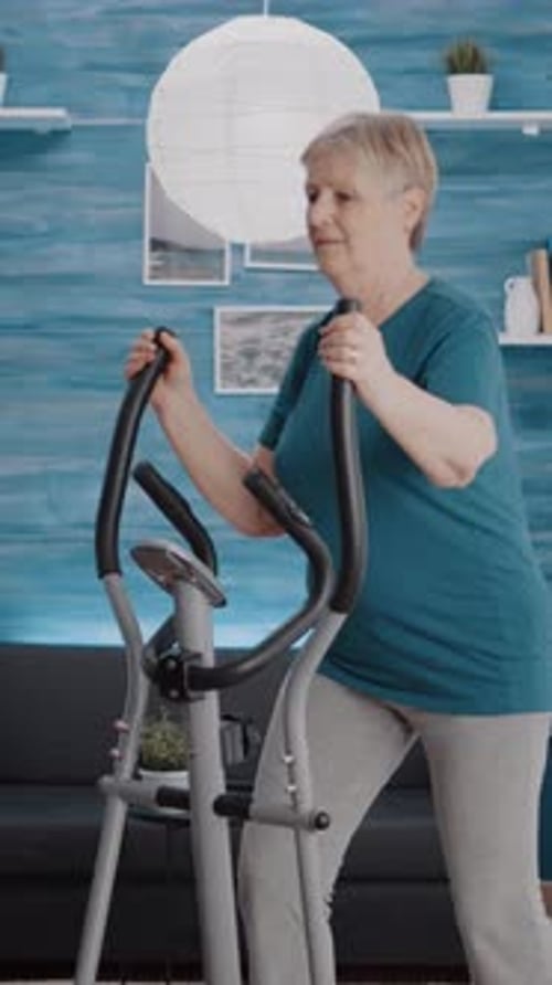 Senior Woman Exercising on Elliptical Machine at Home
