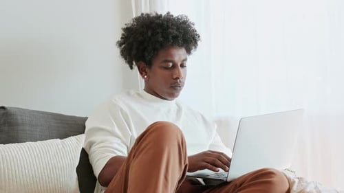 Young Adult Typing on Laptop at Home