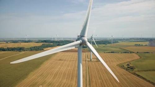 Close up view of spinning blades on wind energy tower. Windmill turning in breeze generates electric