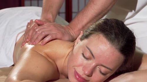 Radiant Woman Blissfully Enjoying a Soothing Back Massage at a Serene Spa