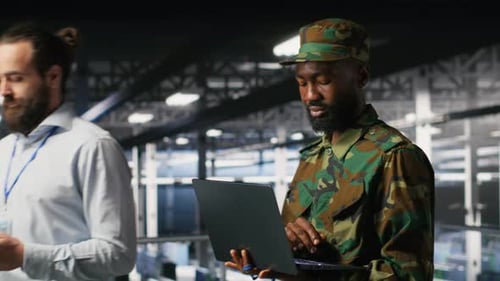Army Technician in Command Center Server Room Using Laptop