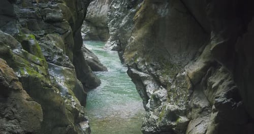 Mountain river with emerald green fresh water flows in rocky gorge