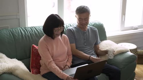 Senior Couple Using Laptop Together on Couch Indoors