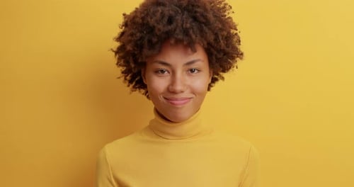 Smiling Woman with Curly Hair Against Yellow Background