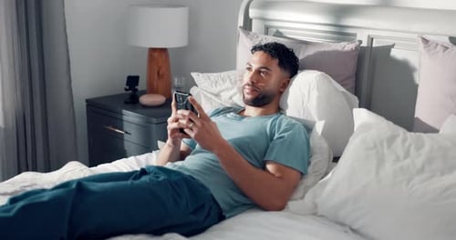 Man Reclining in Bed Using Smartphone