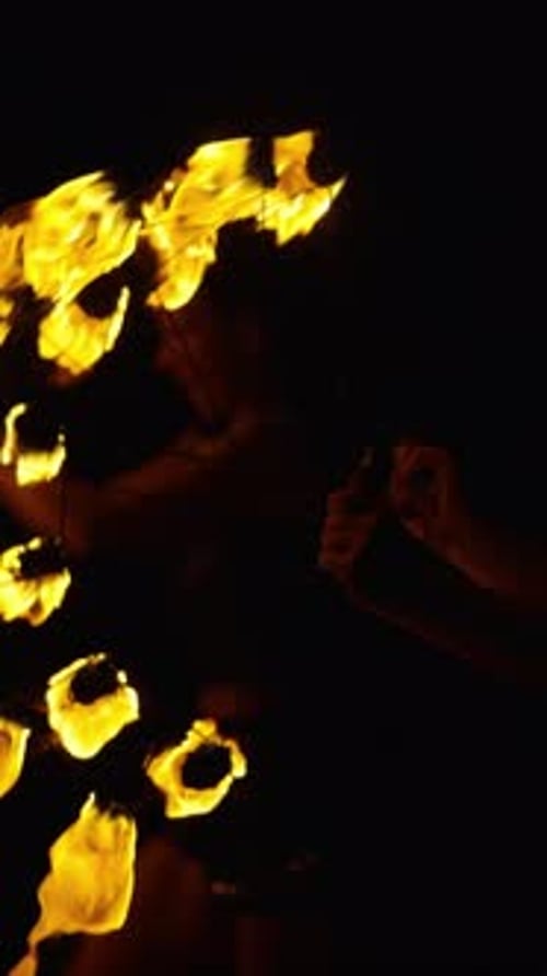 Dynamische Feuerperformance mit sich drehenden Requisiten und einem silhouettierten Darsteller, der für Dramatisch sorgt
