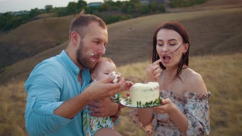 Happy Family with Baby Celebrate First Year Eat Cake in Field at Sunset Autumn and Lifestyle