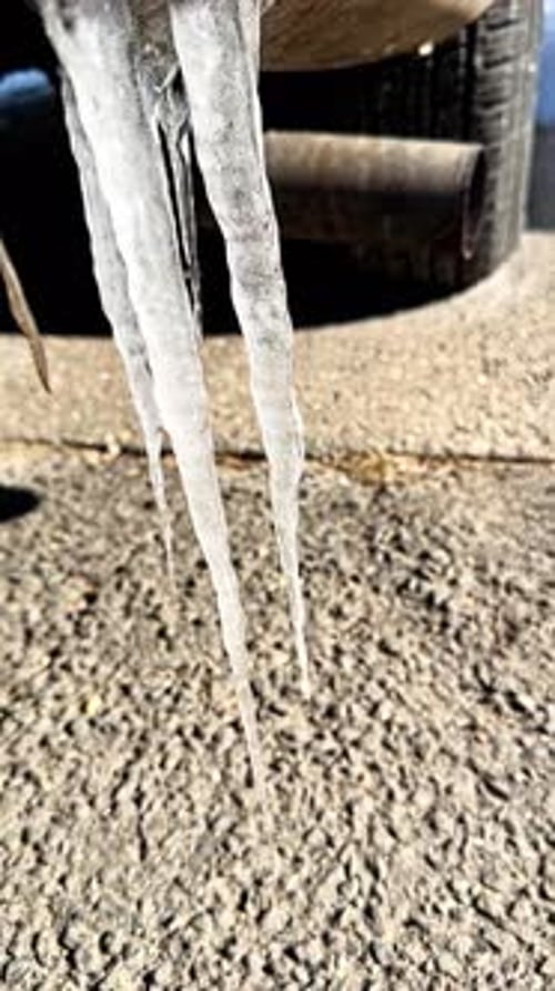 Icicles Hanging near a Car Exhaust in Winter