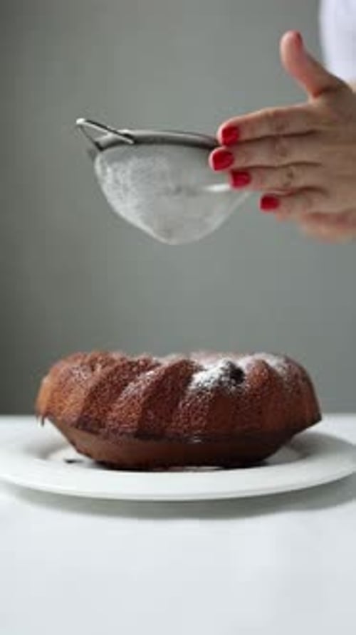 A woman in a home kitchen preparing a cupcake