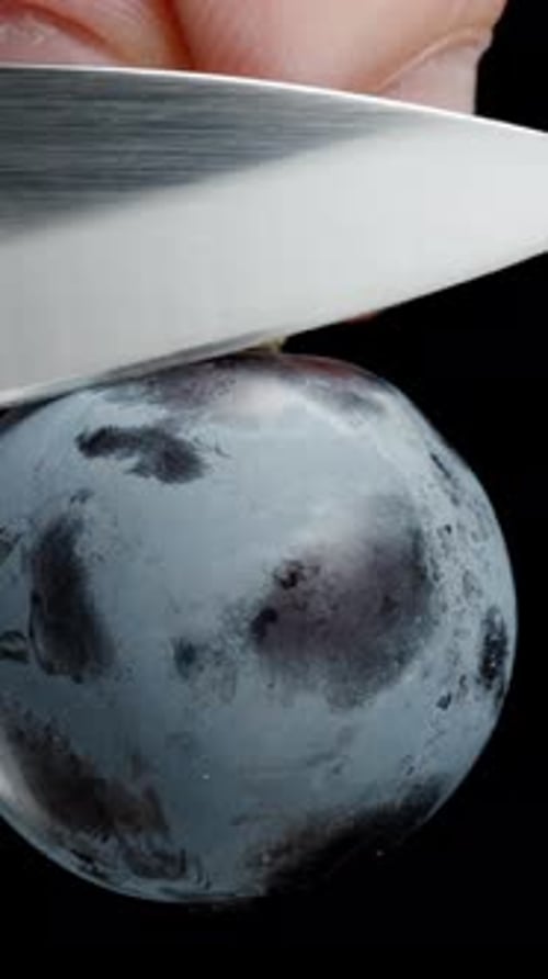 Vertical video. A halved Black Grape berry with seeds inside, cyclically rotating on a black.
