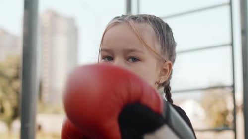 Young Caucasian Girl in Boxing Gloves Looking at the Camera with a Confident Face and Showing Some