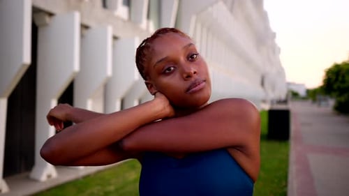 Young Woman Stretching Arms Outside Urban Building