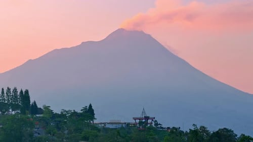 Drone view of building on the highland with active Merapi Volcano and sunrise sky on background. Ket