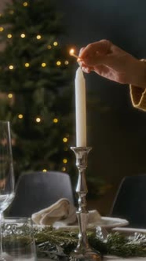 Hand of Woman Lighting Candle in Silver Holder on Festive Dinner Table