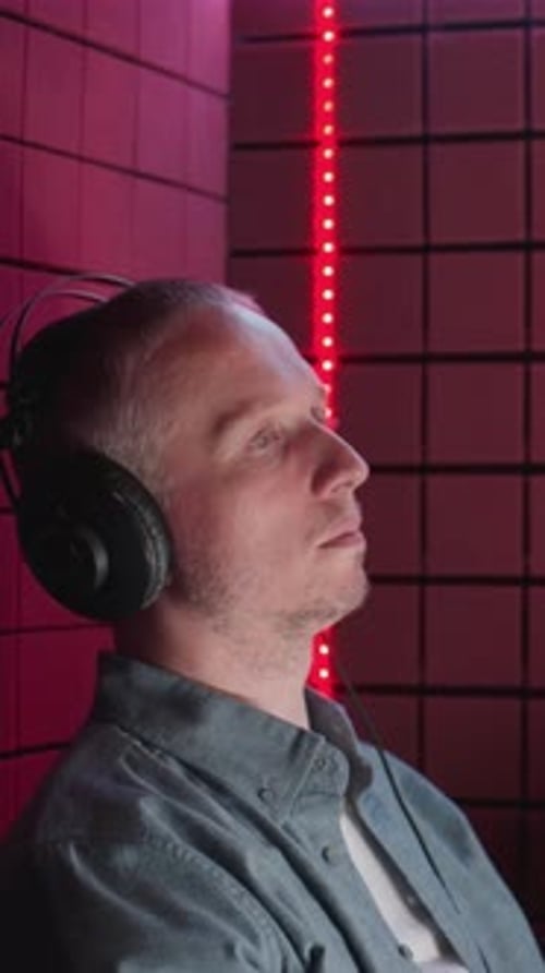 Man in Studio with Headphones Singing Into Microphone