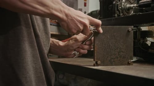 Hands of Male Mechanic Assembling Metal Component with Wrench