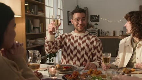 Group of Friends Sharing Meal Around Table, Raising Glasses in a Toast