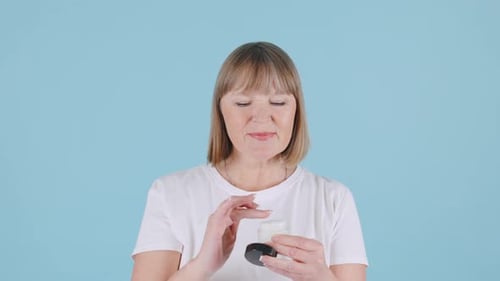 Woman Applies Lotion to Face and Neck