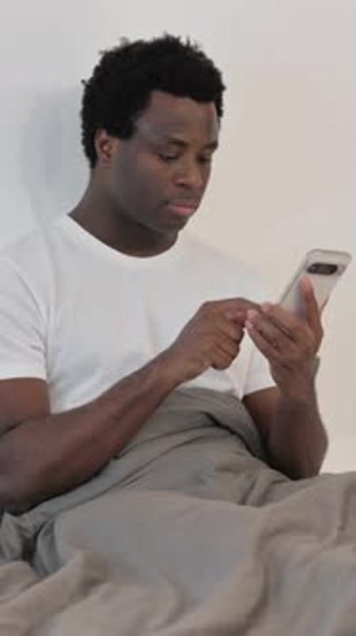 Young Adult Using Smartphone in Bed