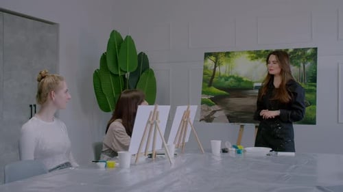 A Woman is Standing in Front of a Painting and Talking to Three Other Women