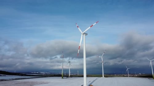 Low angle orbit aerial of Electricity Wind Turbines Farm, Power Clean Alternative Energy with winter