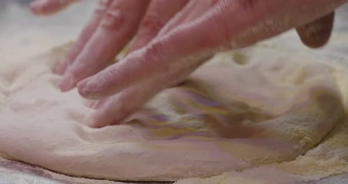 Nahaufnahme der Hände eines Pizzabäcks, der den Teig knetet, um eine Gourmet-Pizza zuzubereiten, und verteilt den Tom