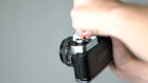 Gros plan d'un jeune film caucasien enroulant à la main dans une caméra analogique vintage