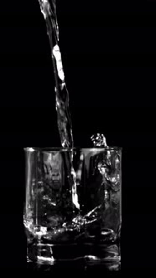 Super Slow Motion Jet of Water Pours Into the Glass on the Table Filmed on a Highspeed Camera at