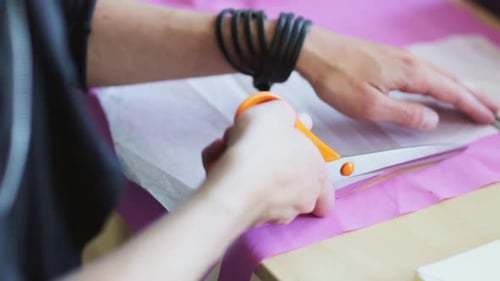 Fashion designer's hands cutting cloth pattern in a bright tailoring workshop