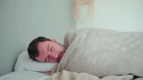 Man Lying Awake in Bed Under Blanket