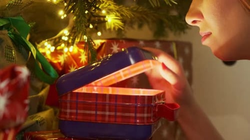 Woman Opening Gift by Christmas Tree