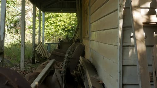 Abandoned farm house with junk on the front porch, TITLT DOWN
