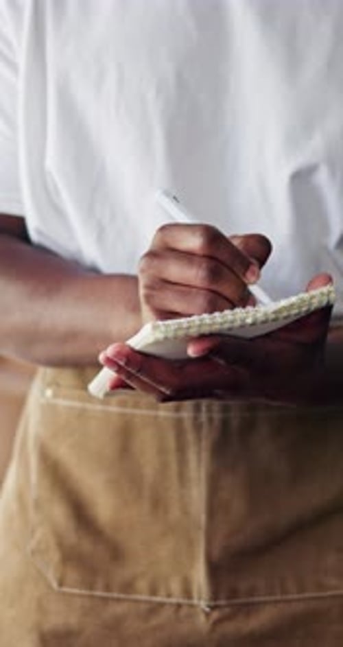 Hands, waiter and writing in book at restaurant for order, decision and checklist for catering