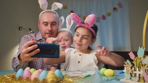 Happy Easter Father And Daughter Enjoying Easter Egg Painting With Bunny Ears